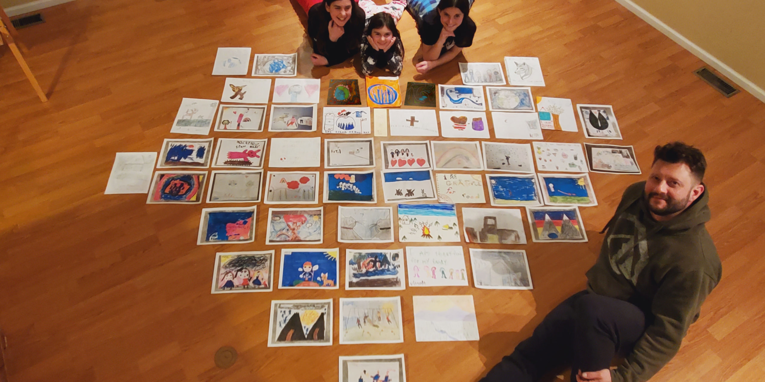 Paolo Gallina with his children and 54 artwork submissions. Photo courtesy of Paolo Gallina.