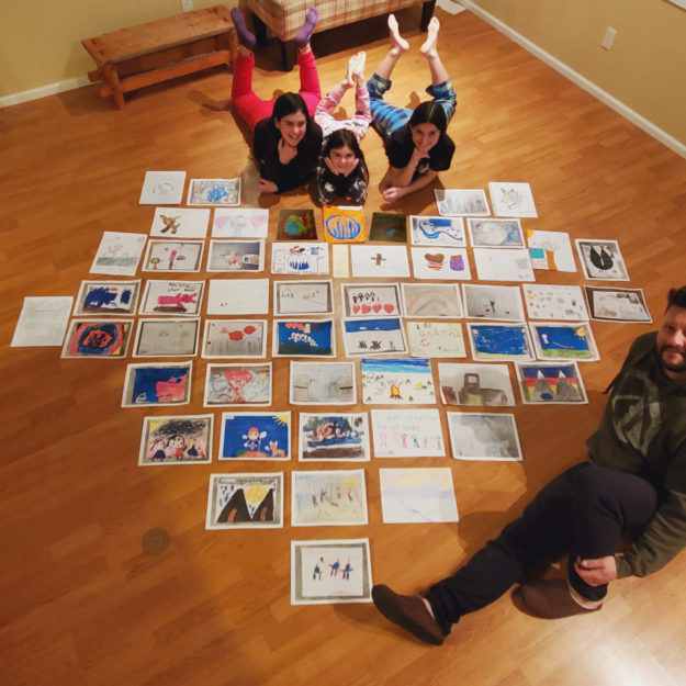 Paolo Gallina with his children and 54 artwork submissions. Photo courtesy of Paolo Gallina.